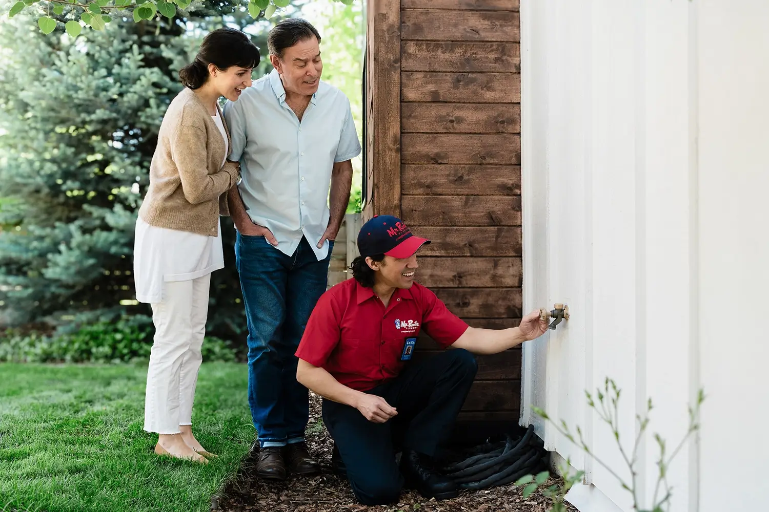 Home owners watching a plumber from Mr Rooter check the outdoor faucet for the hose.