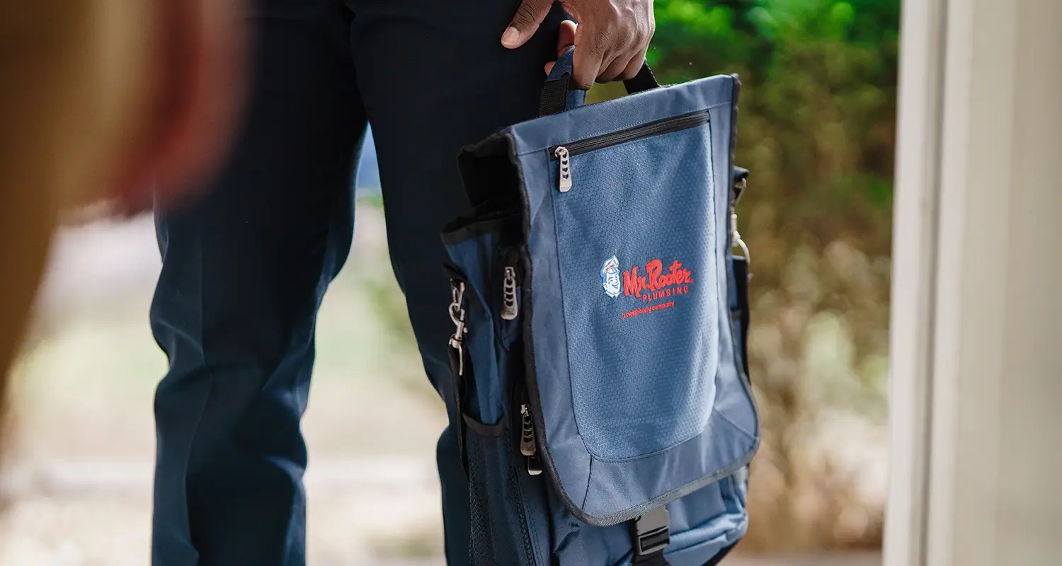 Plumber holding a Mr Rooter tool kit.