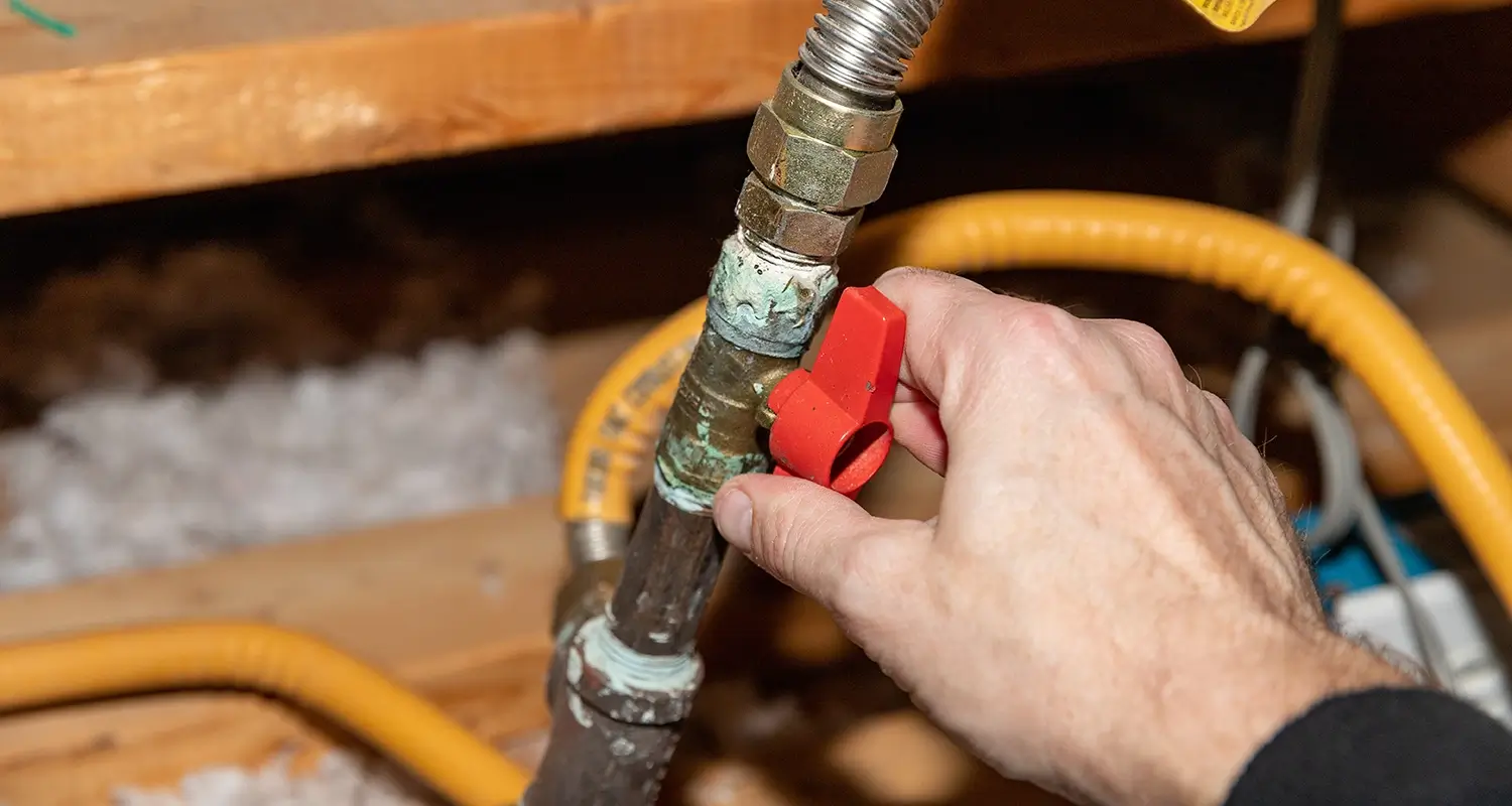 Hand turning the valve on a gas line.