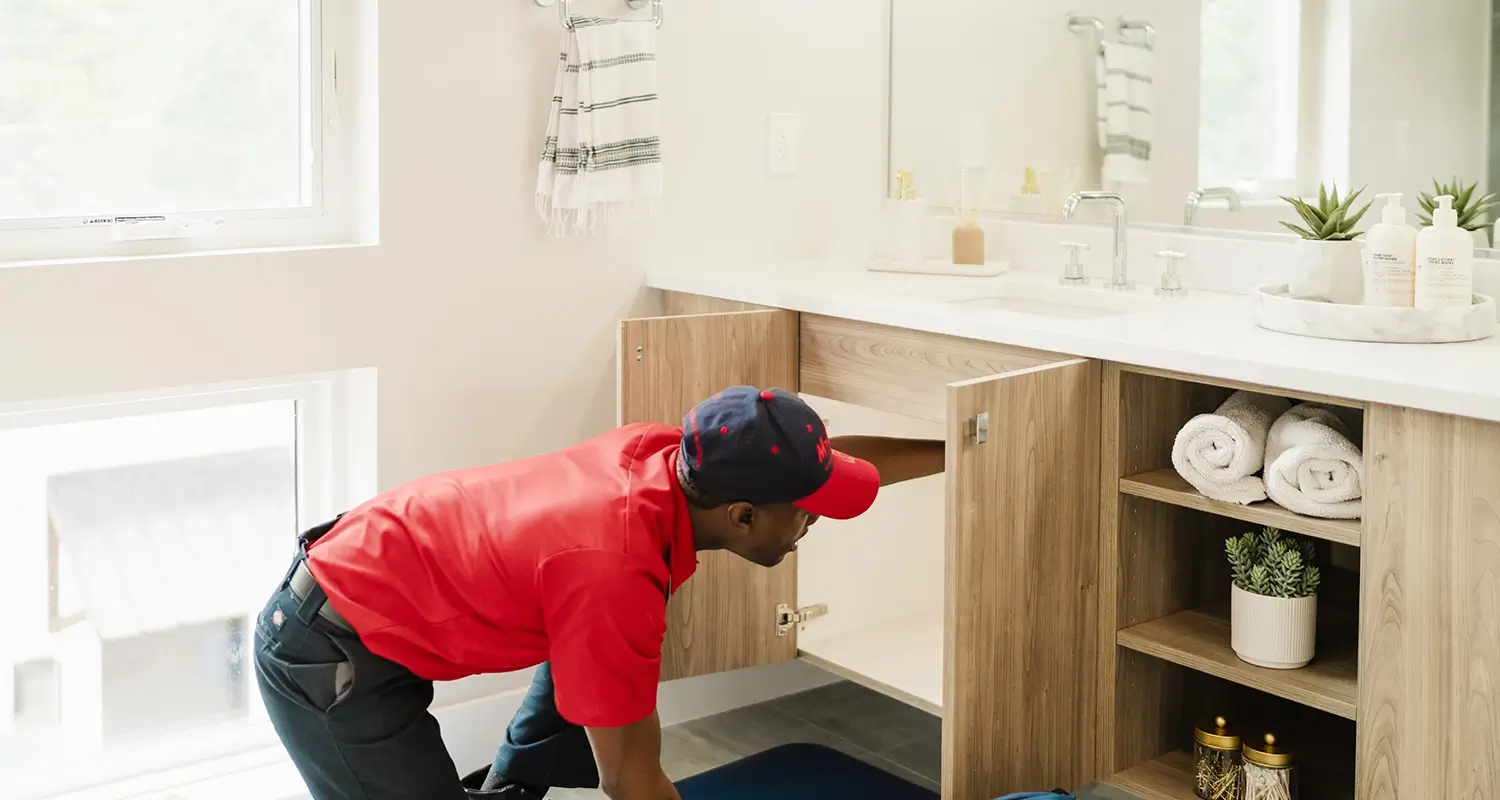 Mr Rooter Expert Plumber working under the sink in a bathroom.