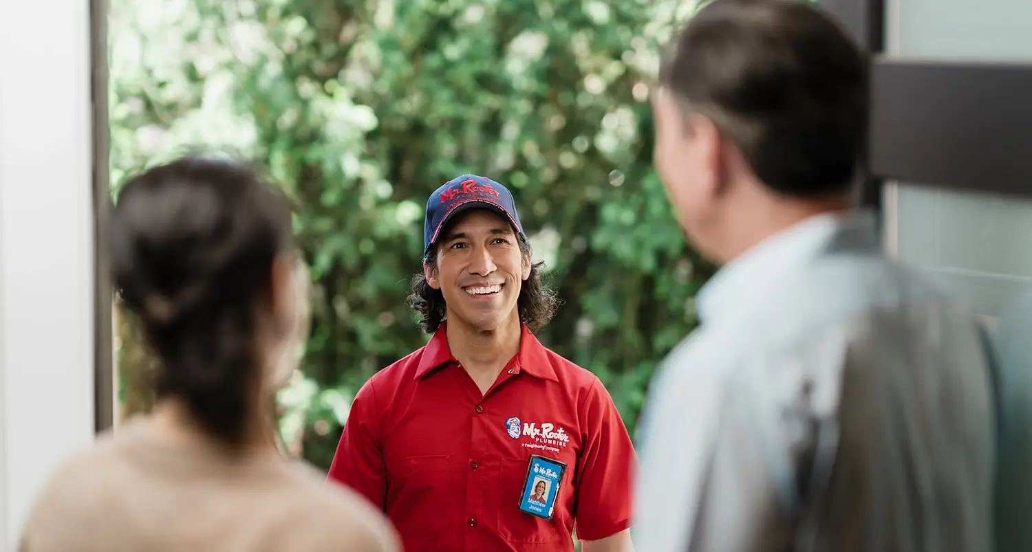 A Mr Rooter Plumbing and Drains expert meeting home owners at the front door.