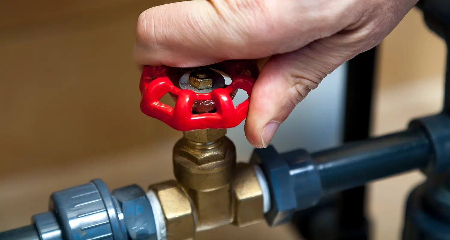 Hand turning a valve on some plumbing.