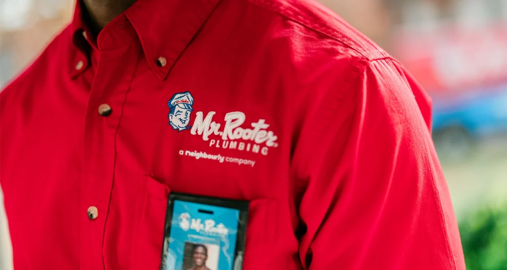 Close up of the Mr Rooter Plumbing logo embroidered on a plumber's shirt.